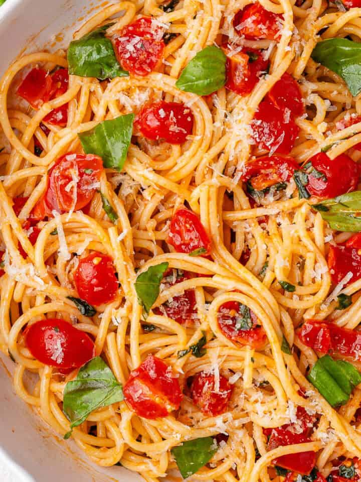 Summer fresh tomato pasta served in a bowl, topped with parmesan cheese and fresh basil