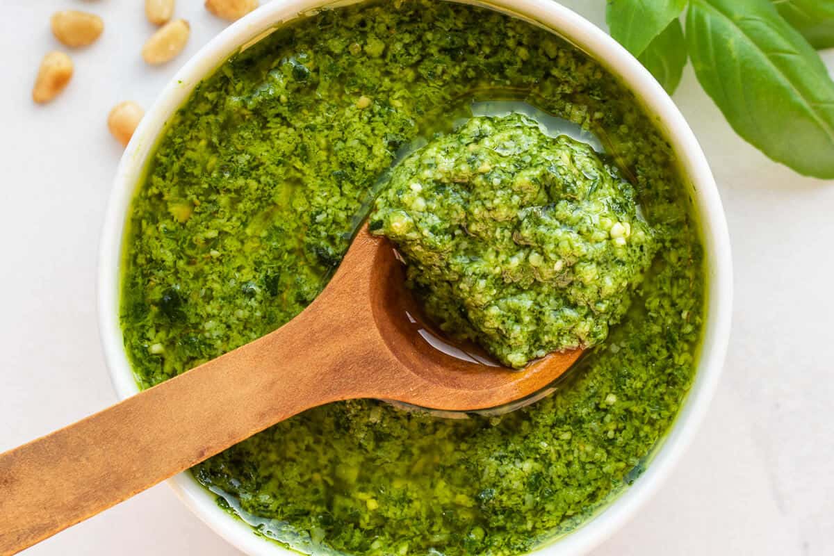 Basil pesto in a small bowl with a wooden spoon