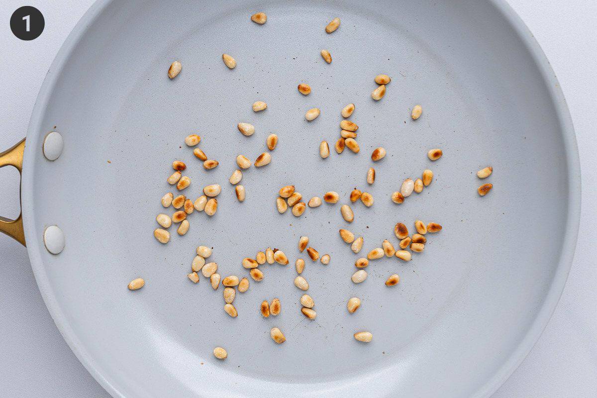 Pine nuts being sautéed in a pan