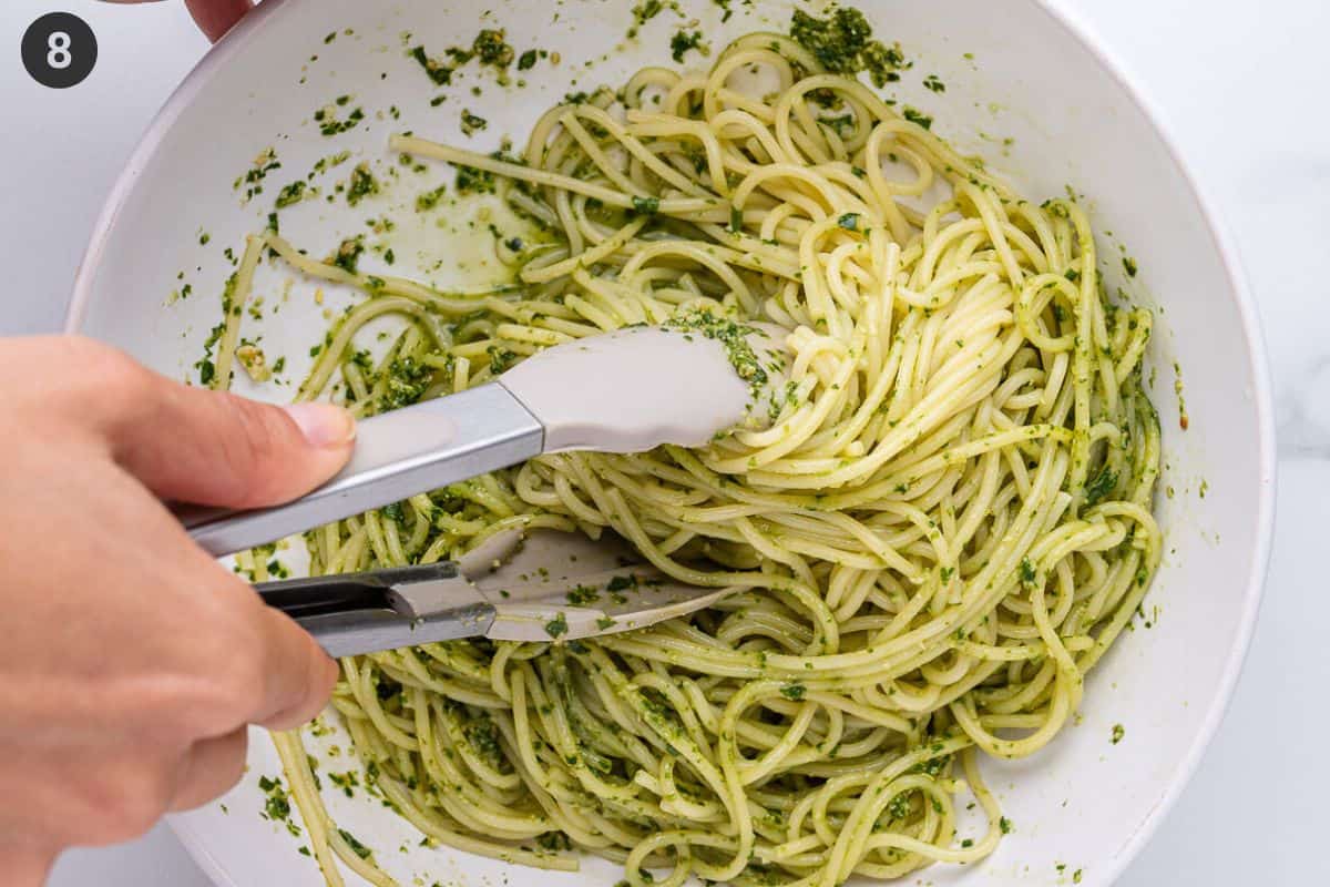 Pesto and pasta mixed together in a bowl