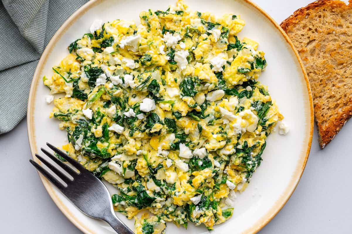Plate of spinach and eggs on a plate with a fork and toast on the side