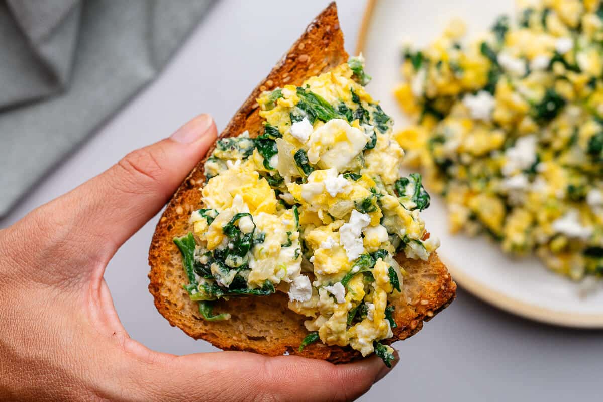 Close up of a piece of toast topped with spinach and eggs