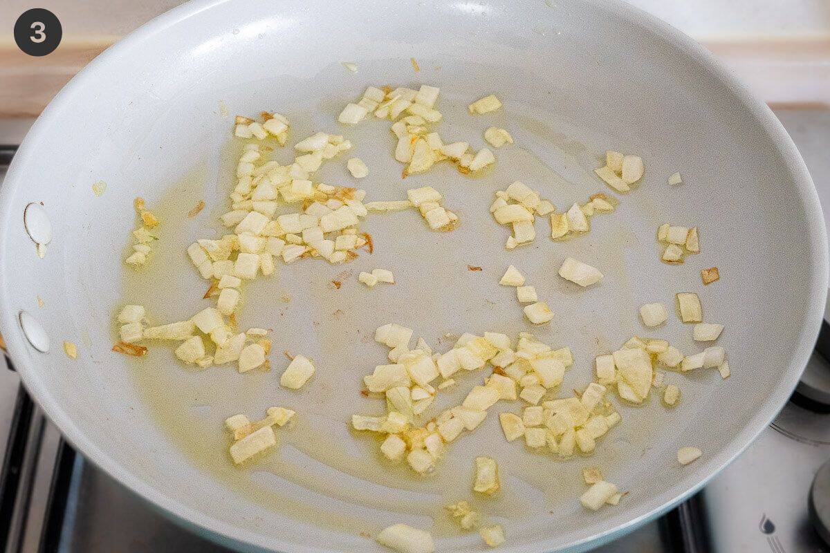 Onion being sautéed in a pan with oil