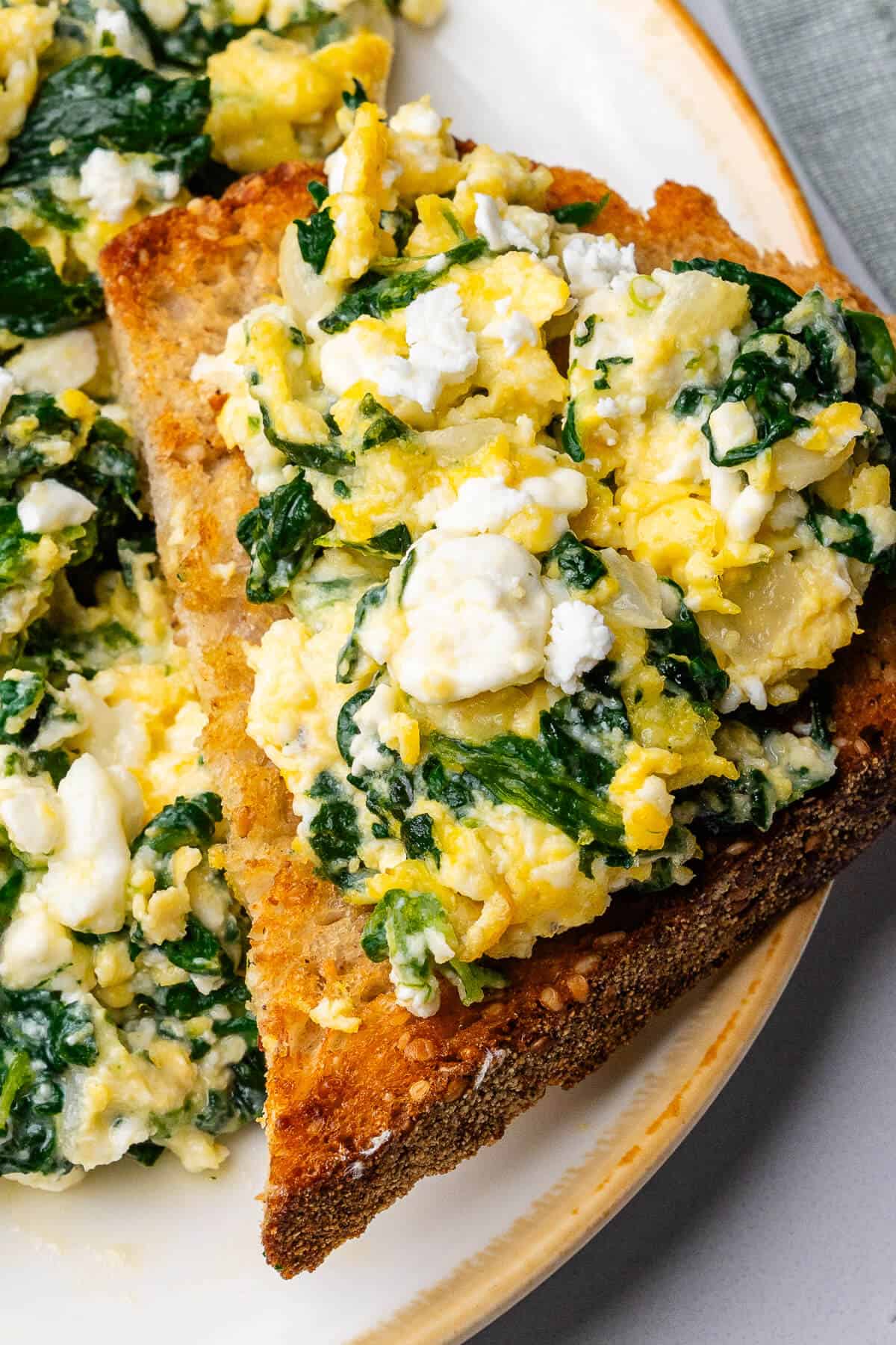 Toast on a plate of spinach scrambled eggs on top