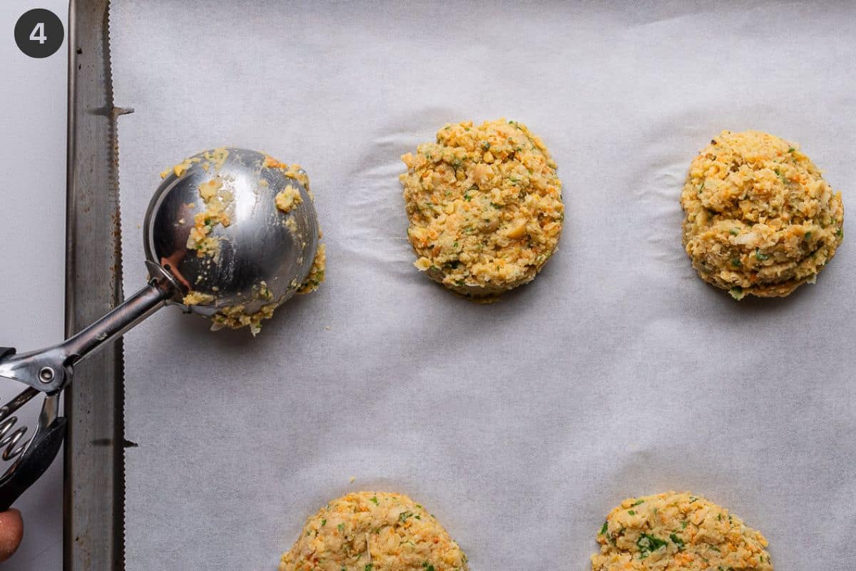 Cookie scoop being used to make fritter shapes on a baking sheet