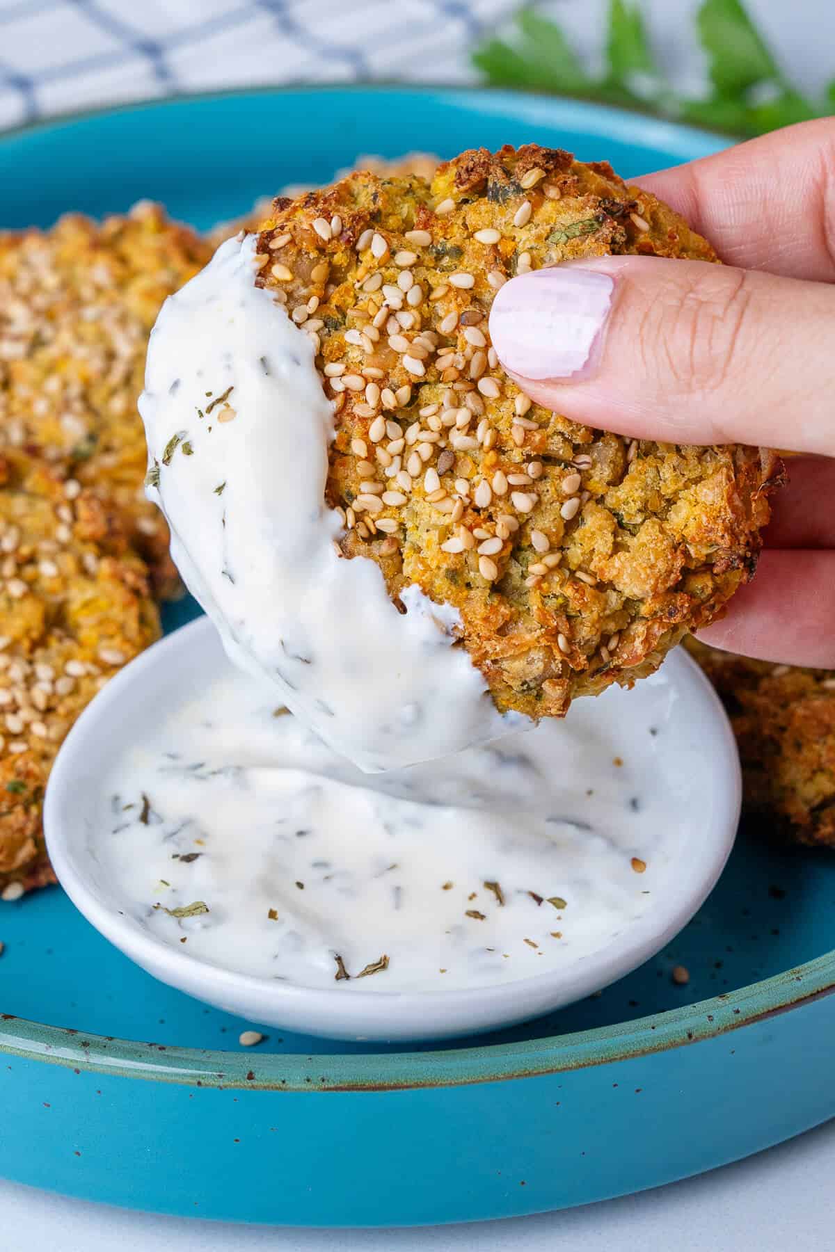 Fritter being dipped into a Greek yogurt sauce