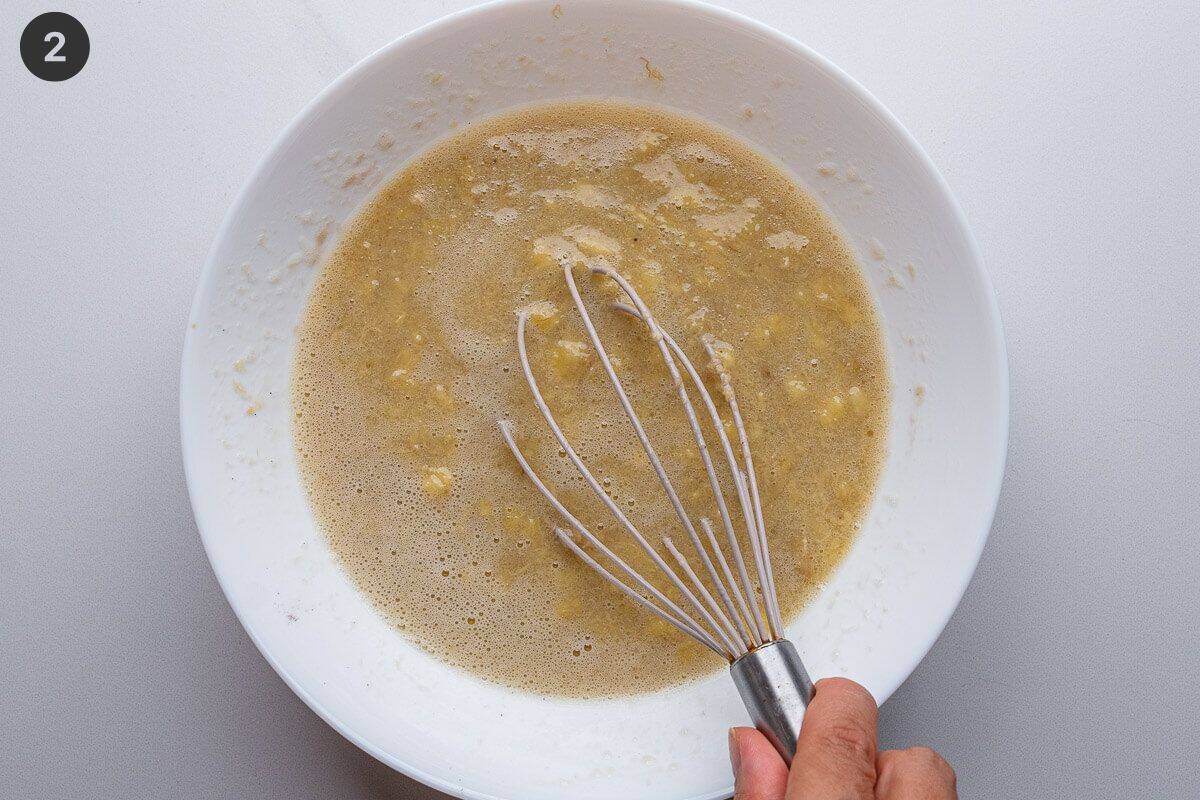 Wet ingredients add to mashed banana in a bowl