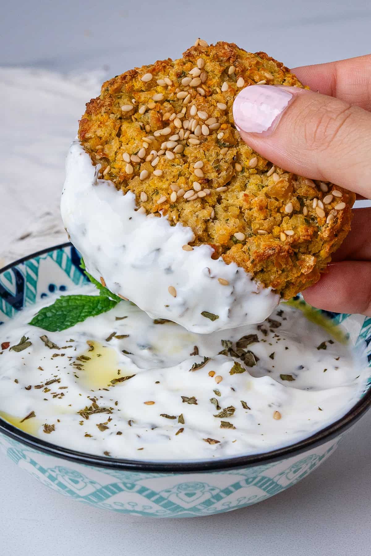 Chickpea fritter being dipped into a Greek yogurt sauce