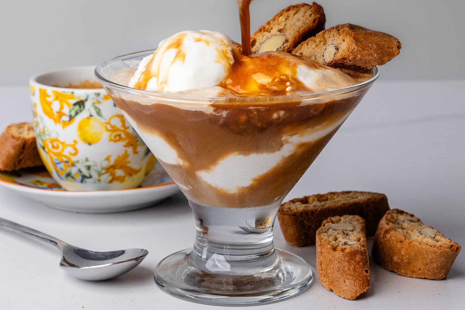 Coffee being poured into a glass cup of vanilla ice cream