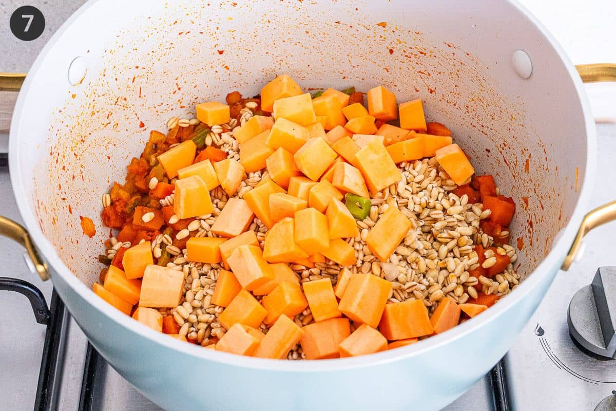 Sweet potatoes and barley being toasted in the pot before liquid is added