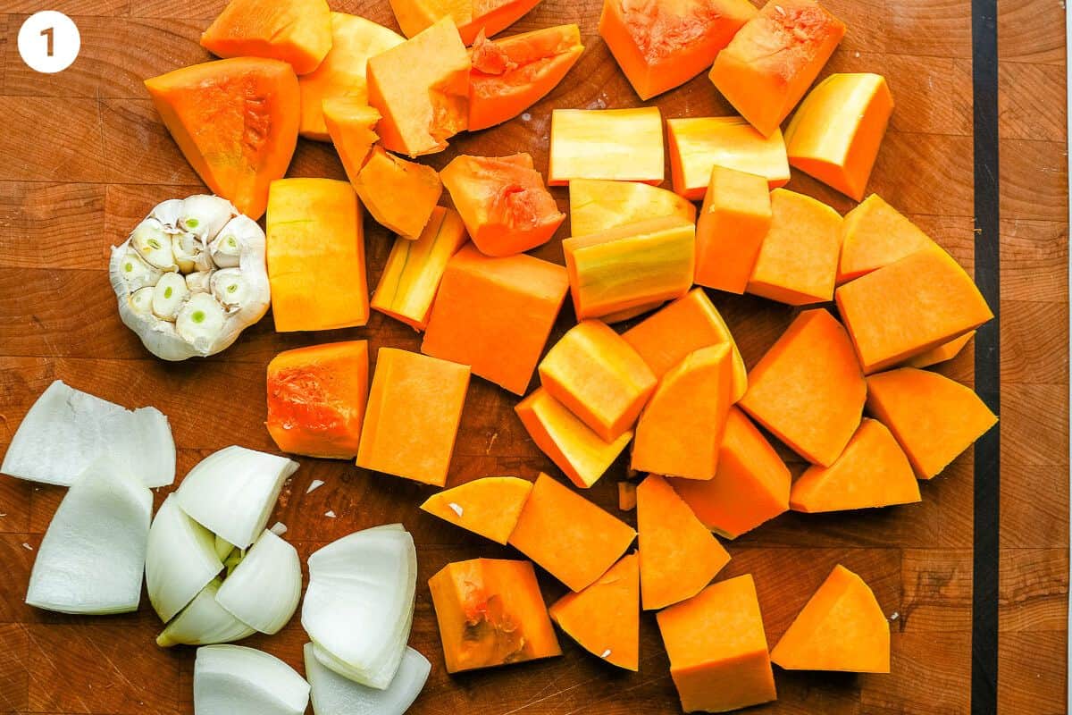 Butternut squash, onion and garlic prepared on a cutting board