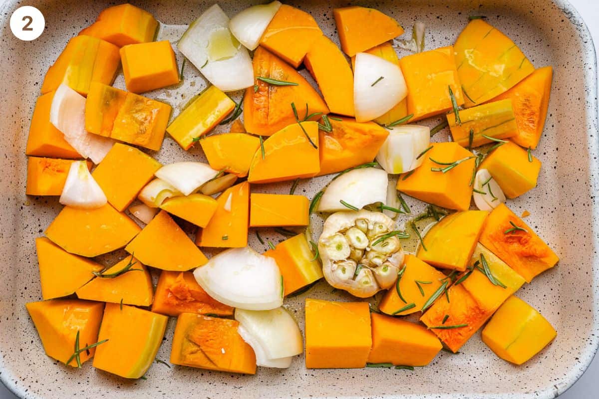 Squash, onion and garlic seasoned with rosemary and olive oil in a baking tray