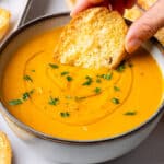 Crostini bread being dipped into a Carrot Soup