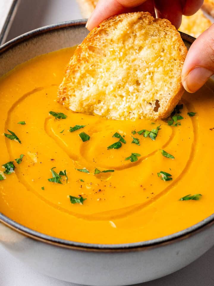 Crostini bread being dipped into a Carrot Soup