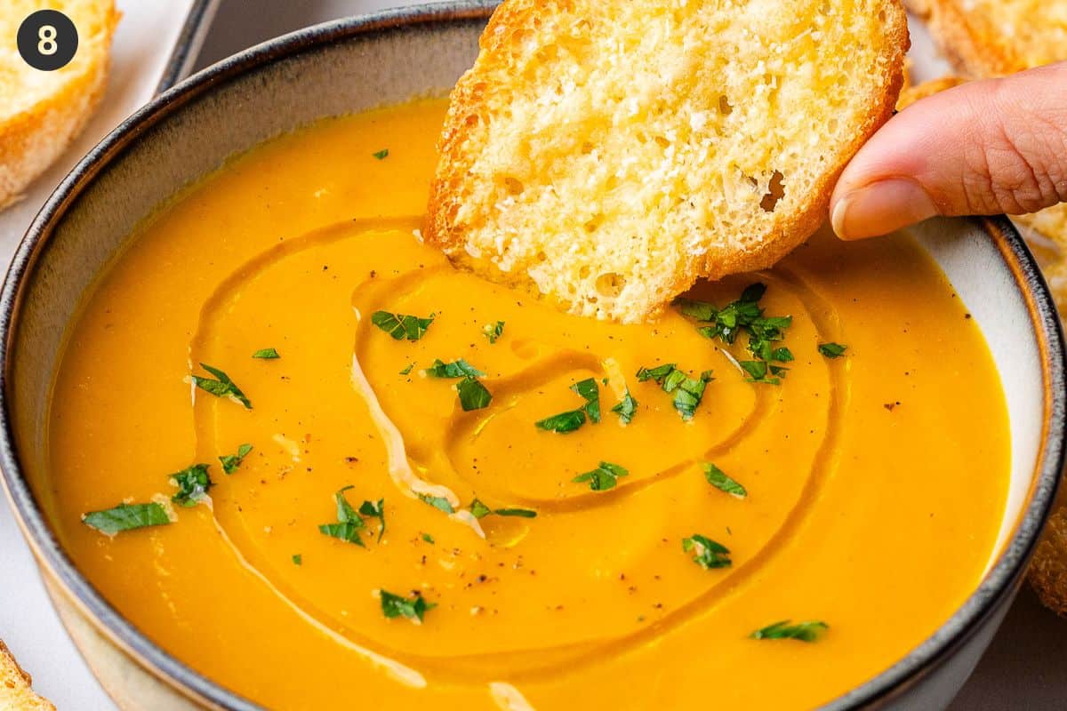 Carrot soup garnished with parsley, olive oil and pepper then dipped with crostini