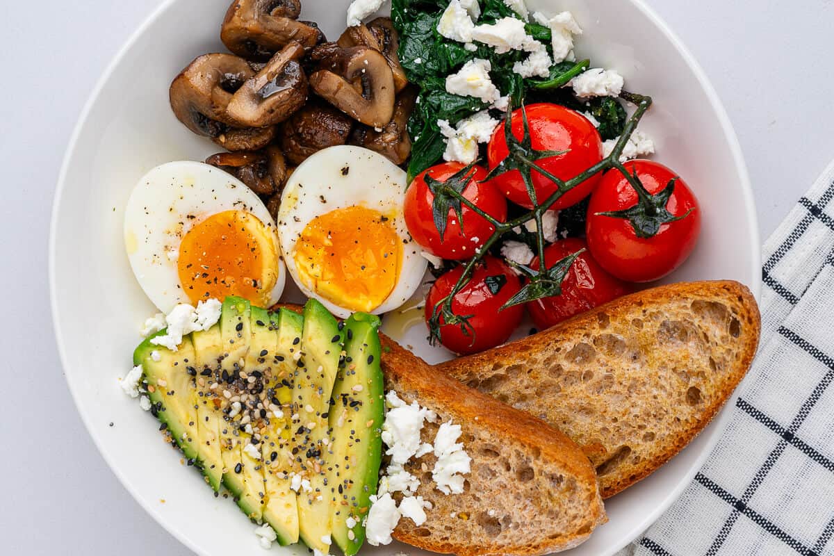 Breakfast bowl with eggs, avocado, toast, mushrooms, spinach feta and cherry tomatoes