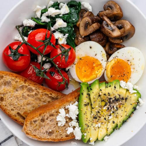 Breakfast bowl with eggs, avocado, toast, mushrooms, spinach and feta and tomatoes