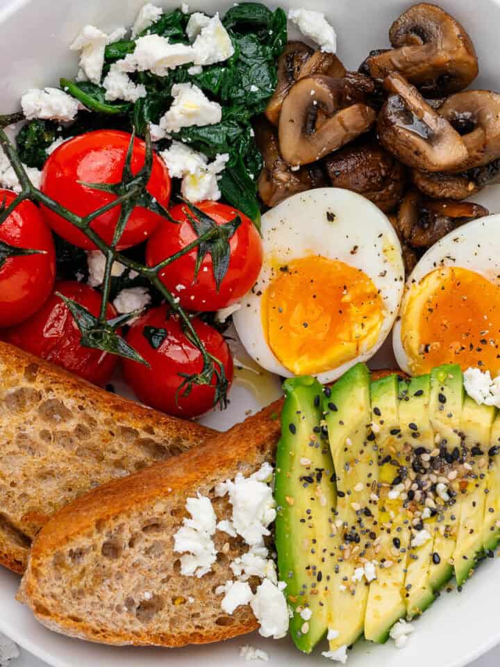 Breakfast bowl with eggs, avocado, toast, mushrooms, spinach and feta and tomatoes