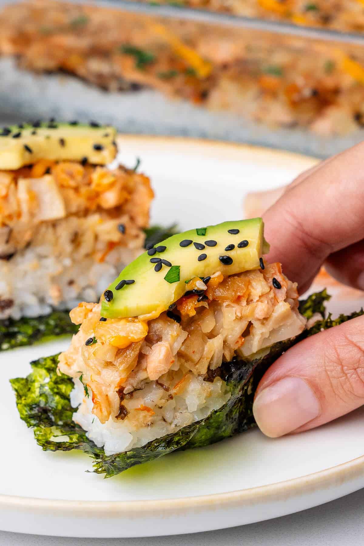 Piece of nori sheet topped with sushi bake being picked up