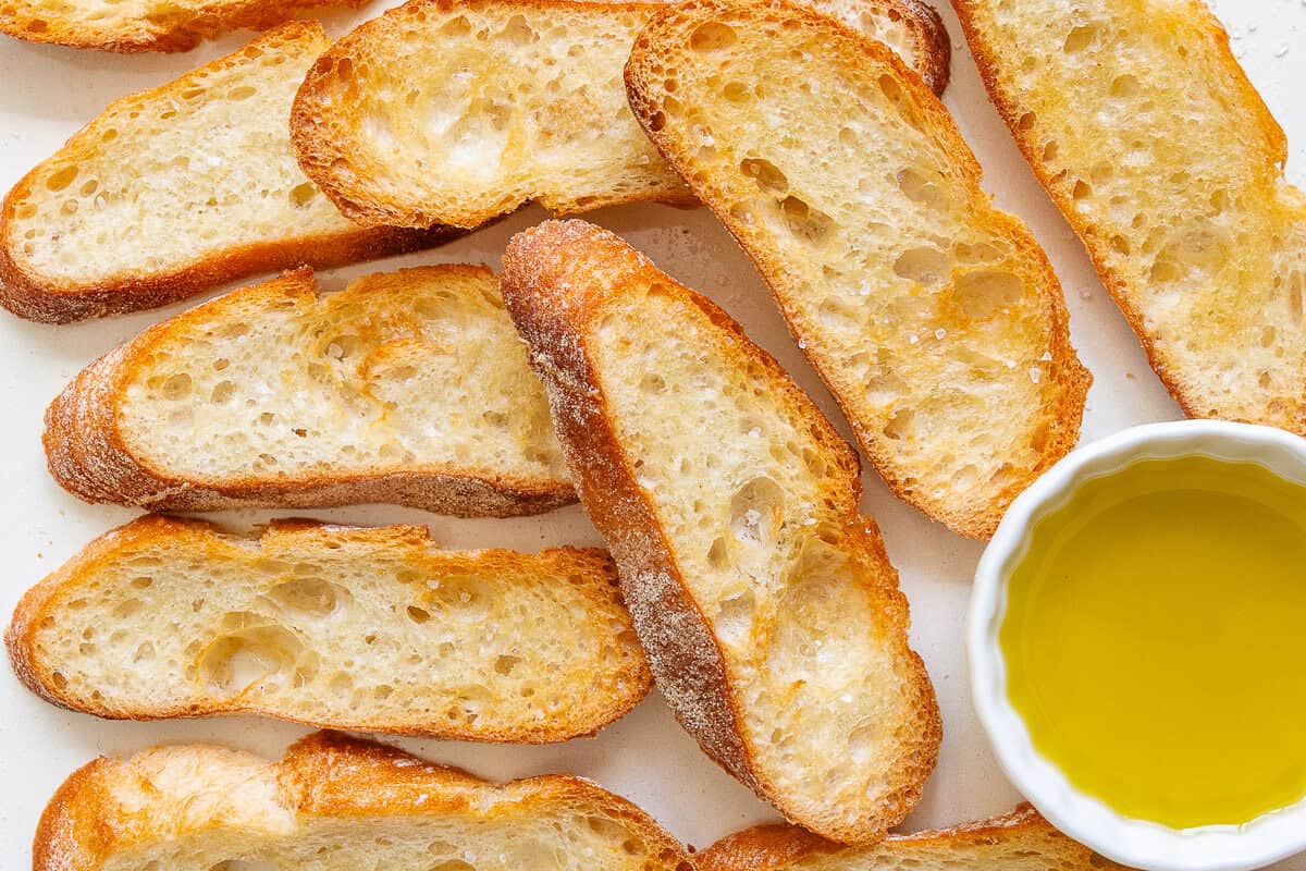 Oven baked crostini on a tray with olive oil on the side