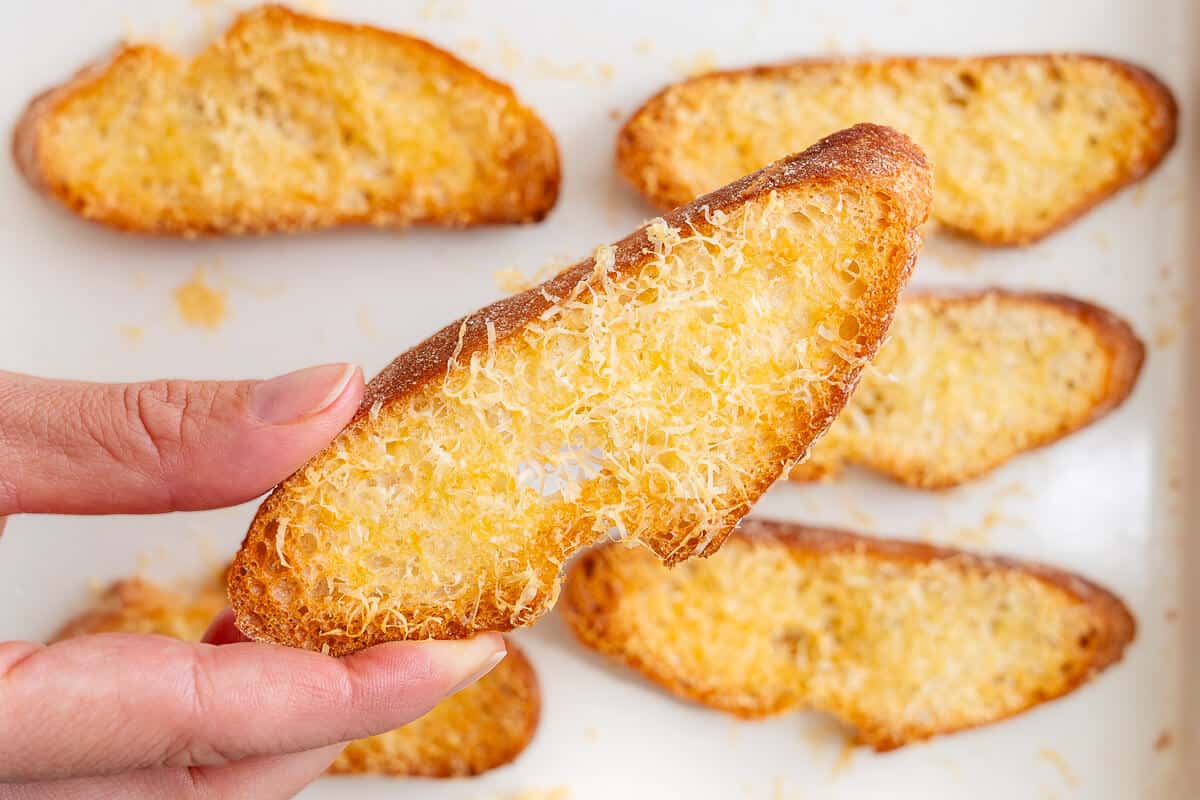 Close up of a piece of crostini with parmesan cheese on top
