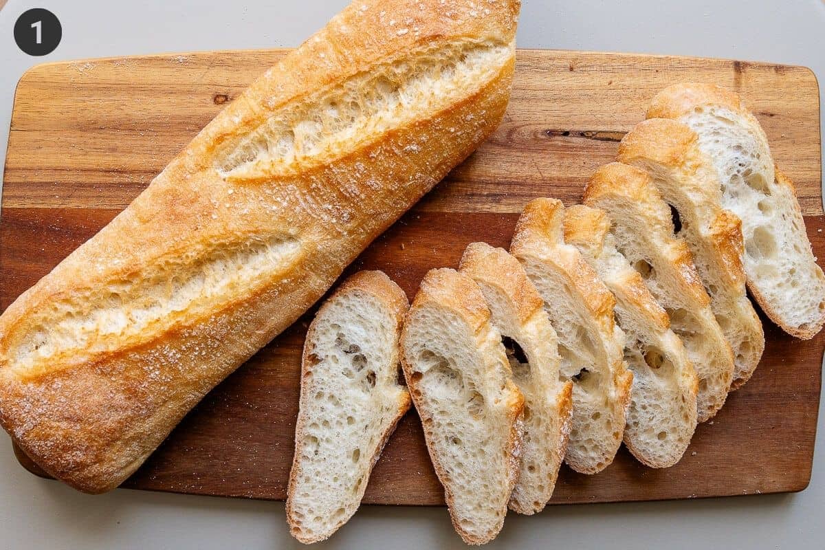Rustic baguette being sliced on a cutting board