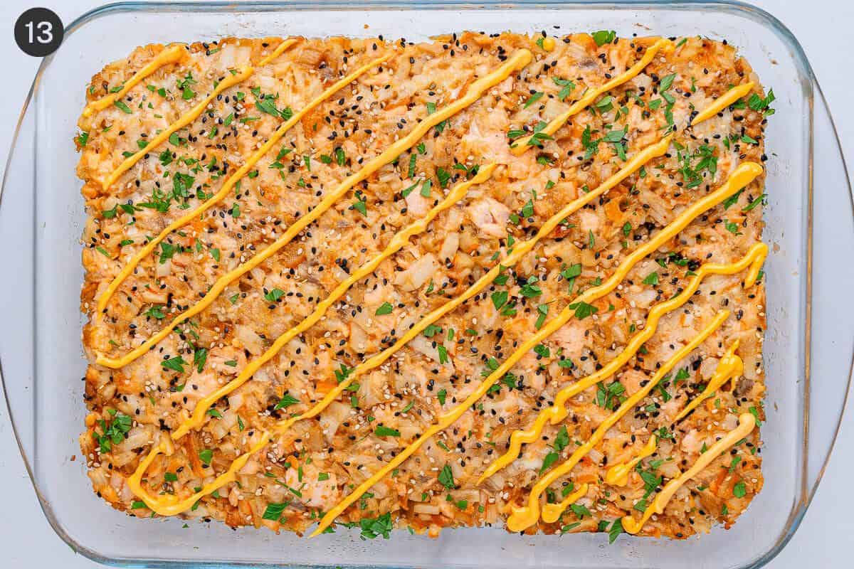 Garnish added on top with spicy sauce drizzled and sesame seeds