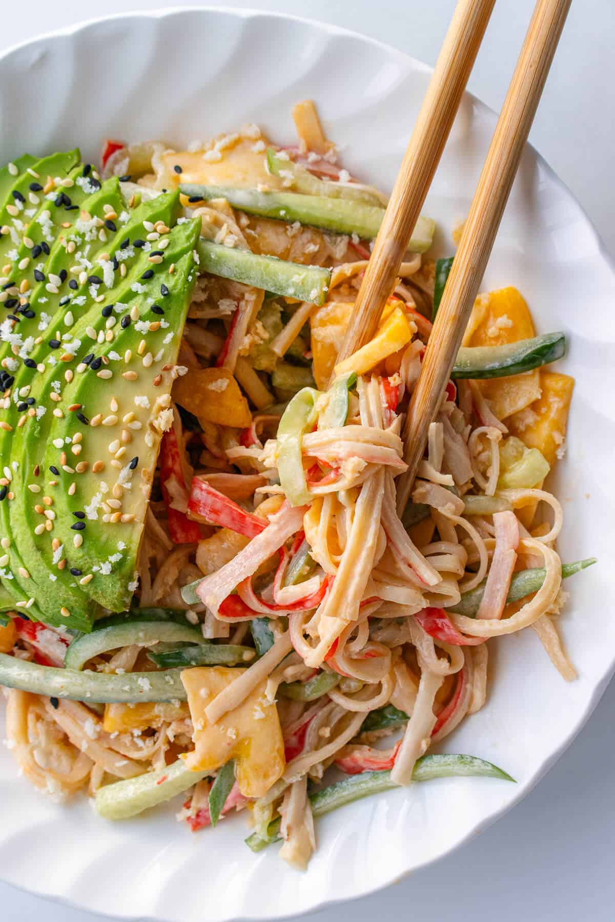 Chopsticks coming out of a bowl of kani salad
