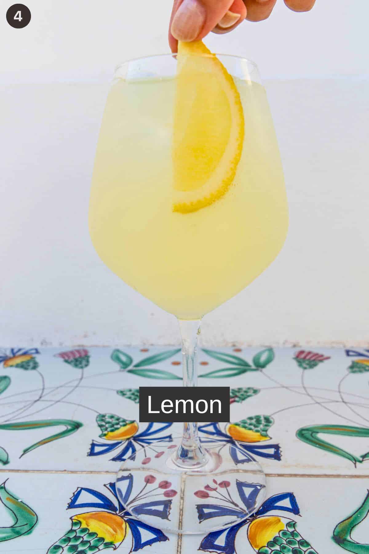 Garnish of lemon wedge added to glass of limoncello spritz