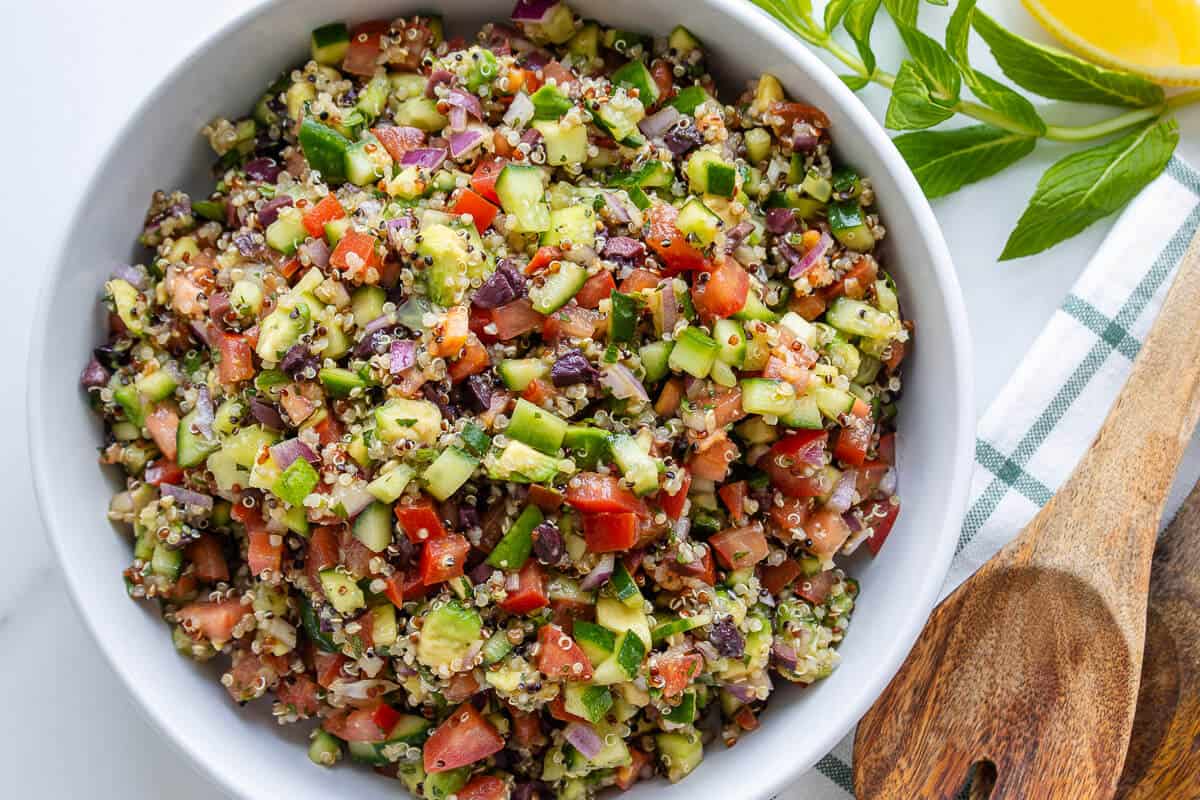 Bowl of quinoa salad with fresh mint and lemon wedge on the side