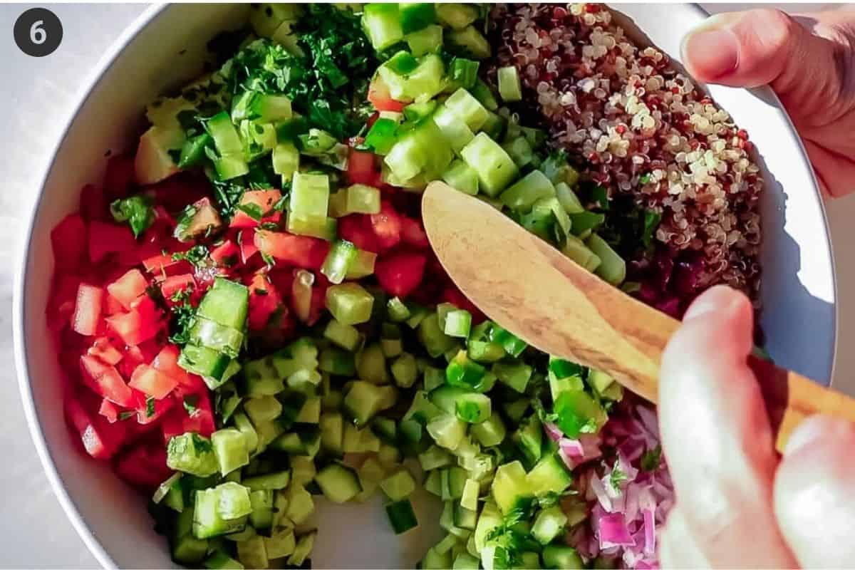 Dressing added to salad bowl and being mixed with a wooden spoon