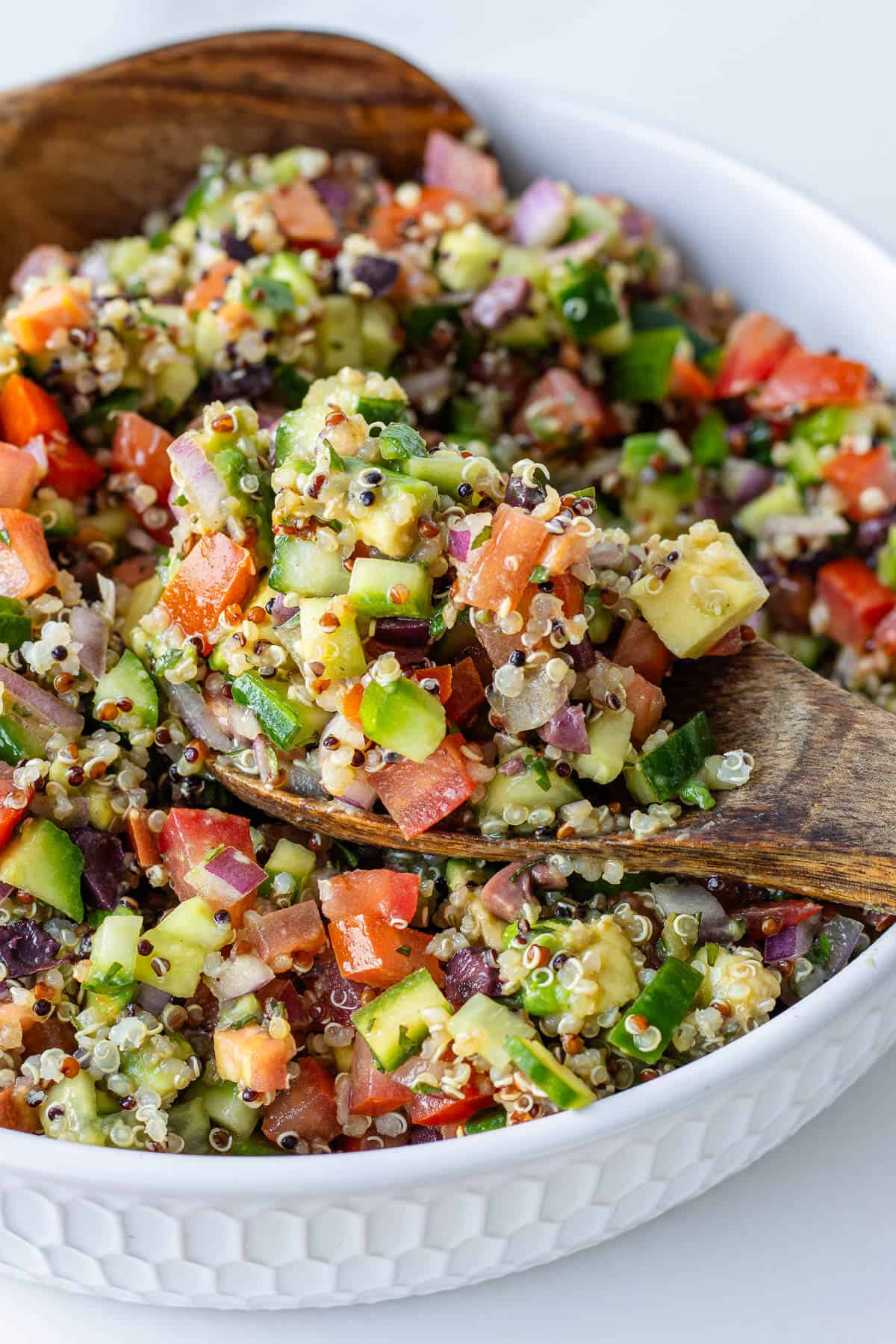 Quinoa salad with a wooden spoon in a bowl