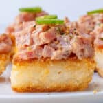 Close up of spicy tuna crispy rice topped with furikake and a slice of jalapeño