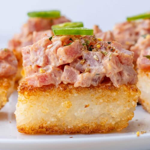 Close up of spicy tuna crispy rice topped with furikake and a slice of jalapeño