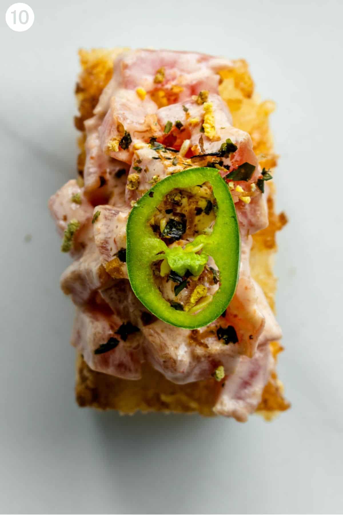 Crispy rice with tuna with a sprinkle of furikake and topped with a slice of jalapeño