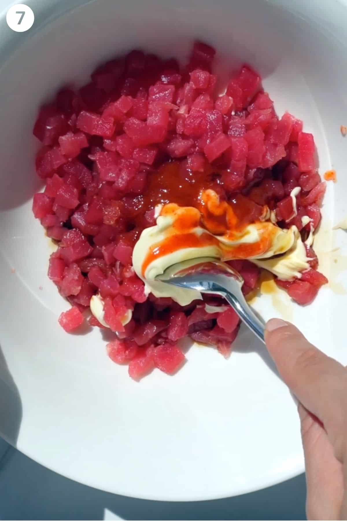 Raw tuna cubes being mixed with spicy mayo sauce