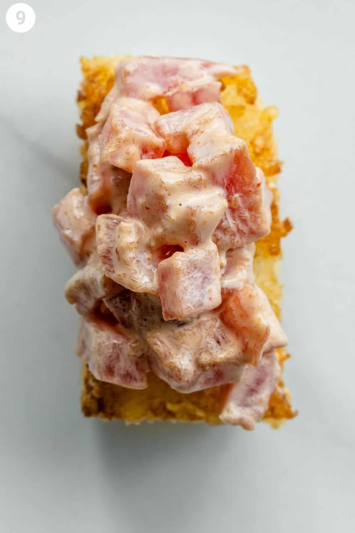 Layering one piece of crispy rice topped with some tuna mixture