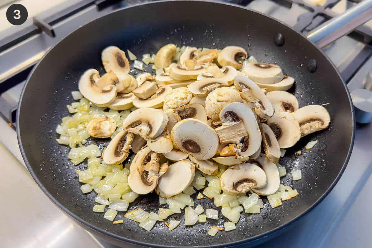 Sliced mushrooms added to onions in a pan