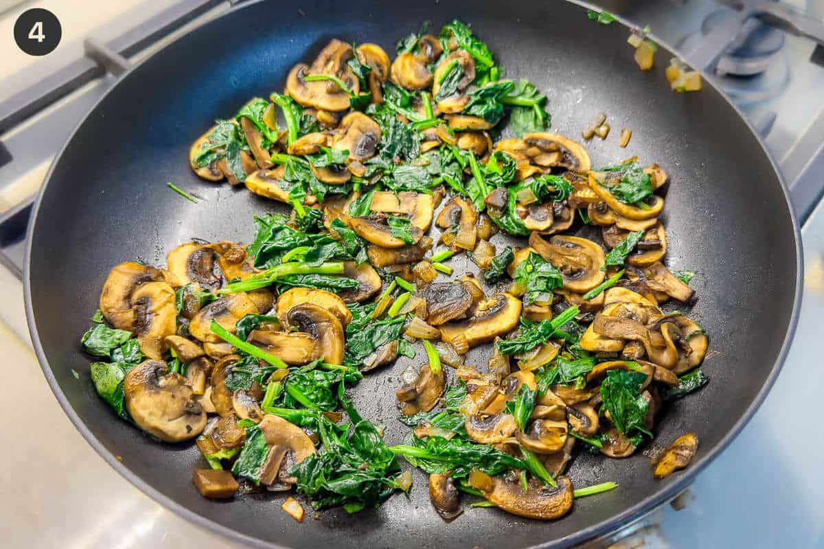 Spinach, mushrooms and onions being sautéed in a pan