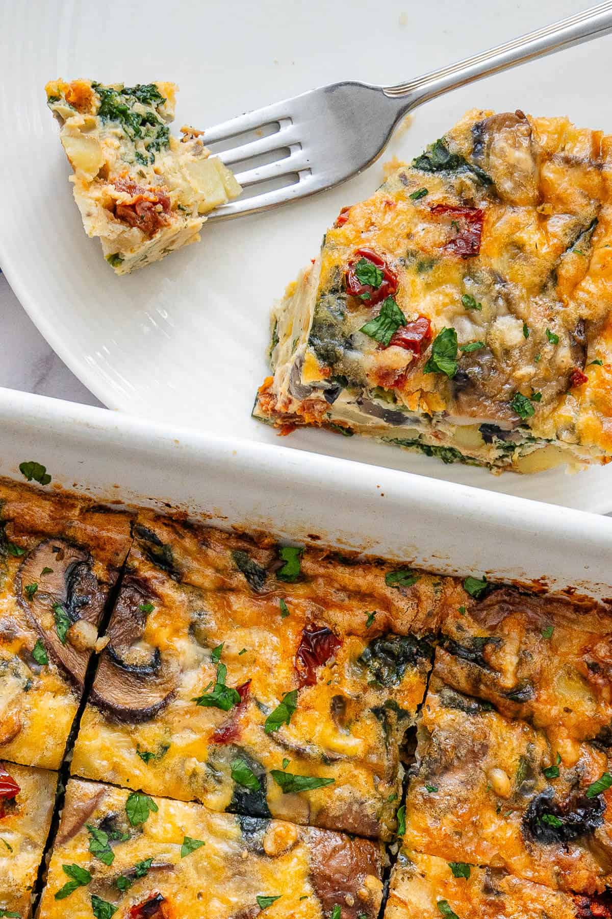 Piece of breakfast casserole with a fork and tray on the side