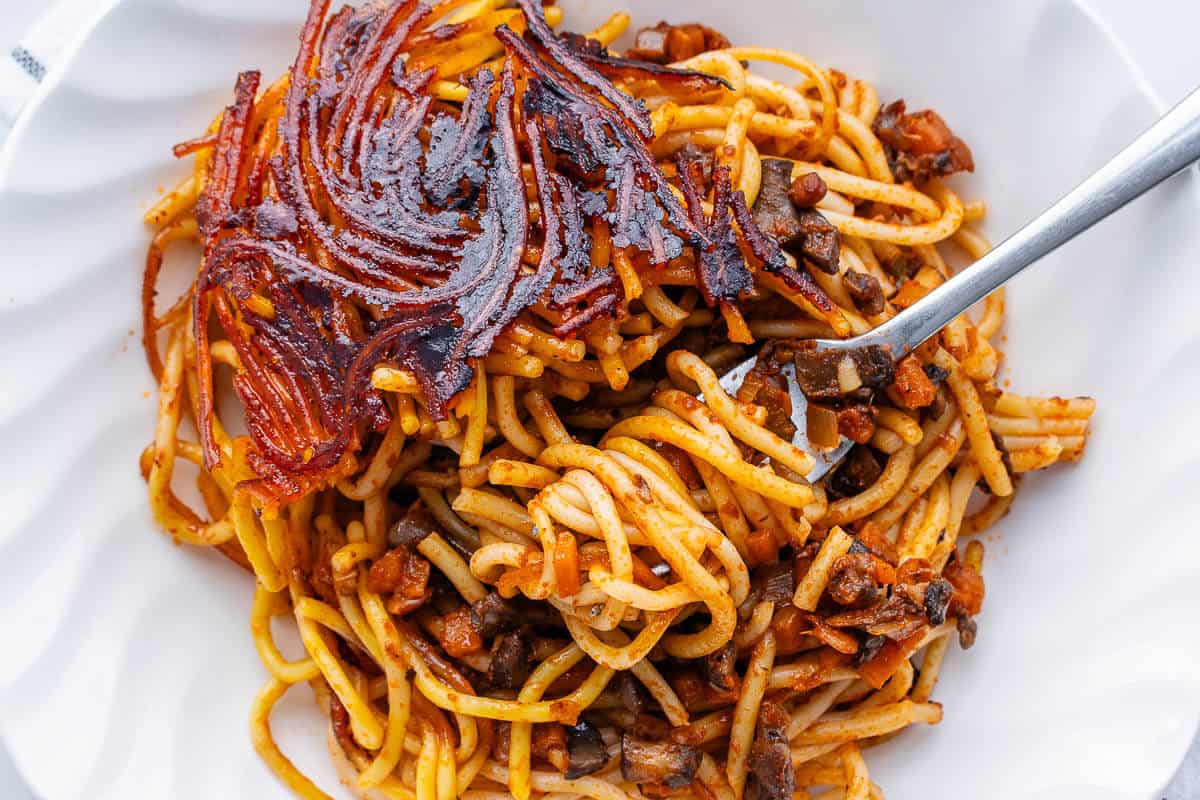 Plate of makaroni with a fork full of pasta and piece of tahdig
