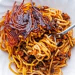 Makaroni Persian spaghetti on a plate with a fork and topped with a piece of tahdig