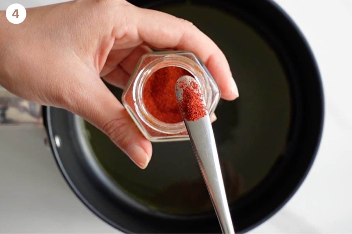 Saffron being added to olive oil at the bottom of a pot