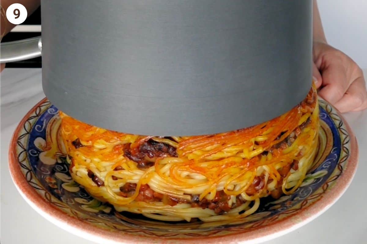 Pot flipped on a large plate then being lifted to expose the makaroni cake