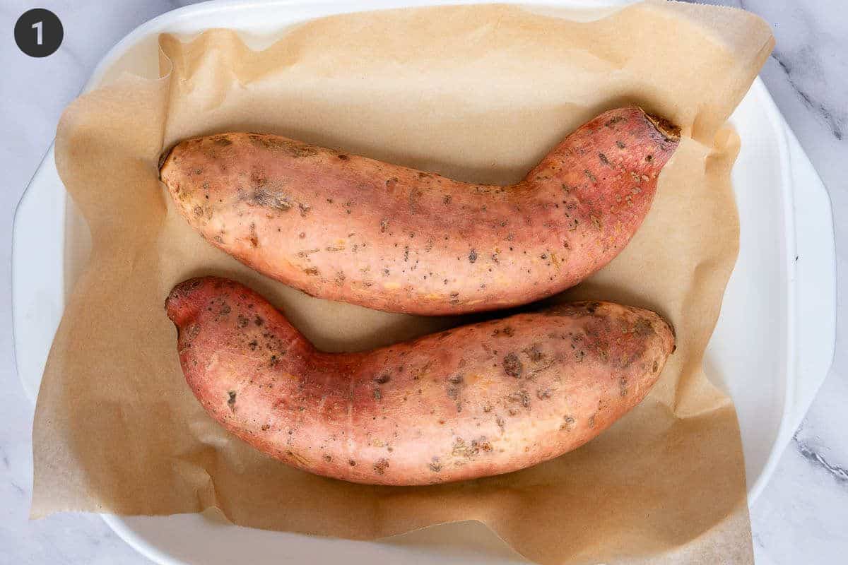 Sweet potato cut in half on an oven tray before being baked