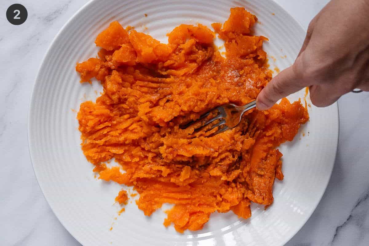 baked sweet potato being mashed with a fork