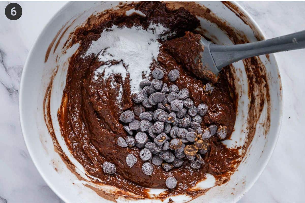 Chocolate chips and baking powder being folded into batter