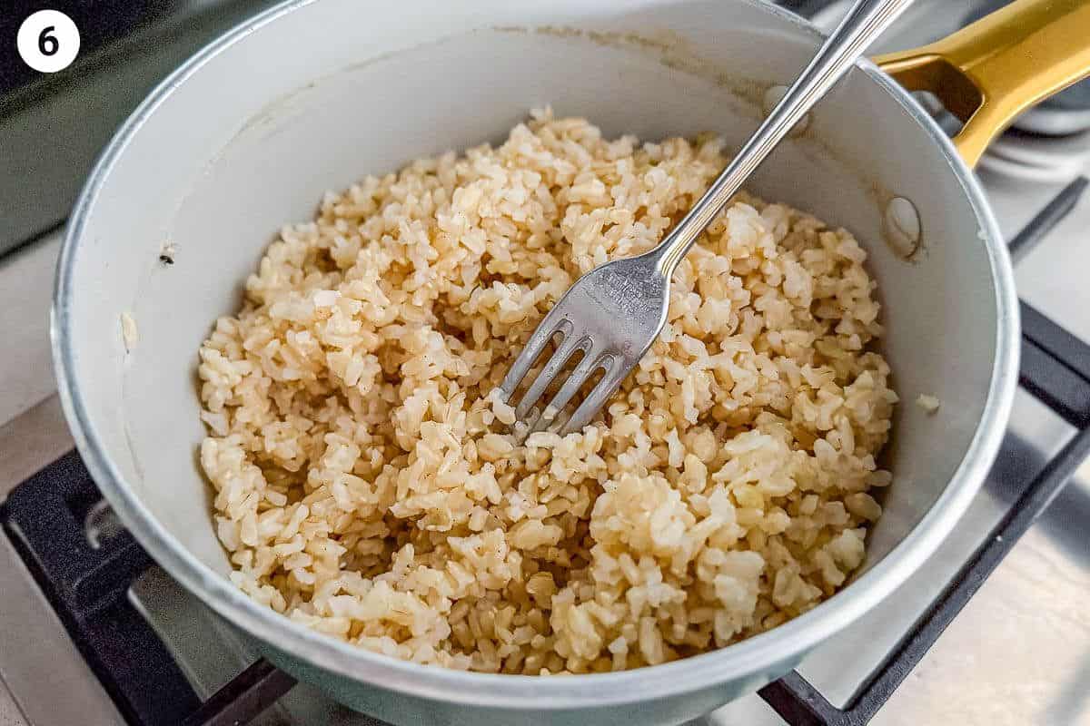Fork fluffing the brown rice after being steamed
