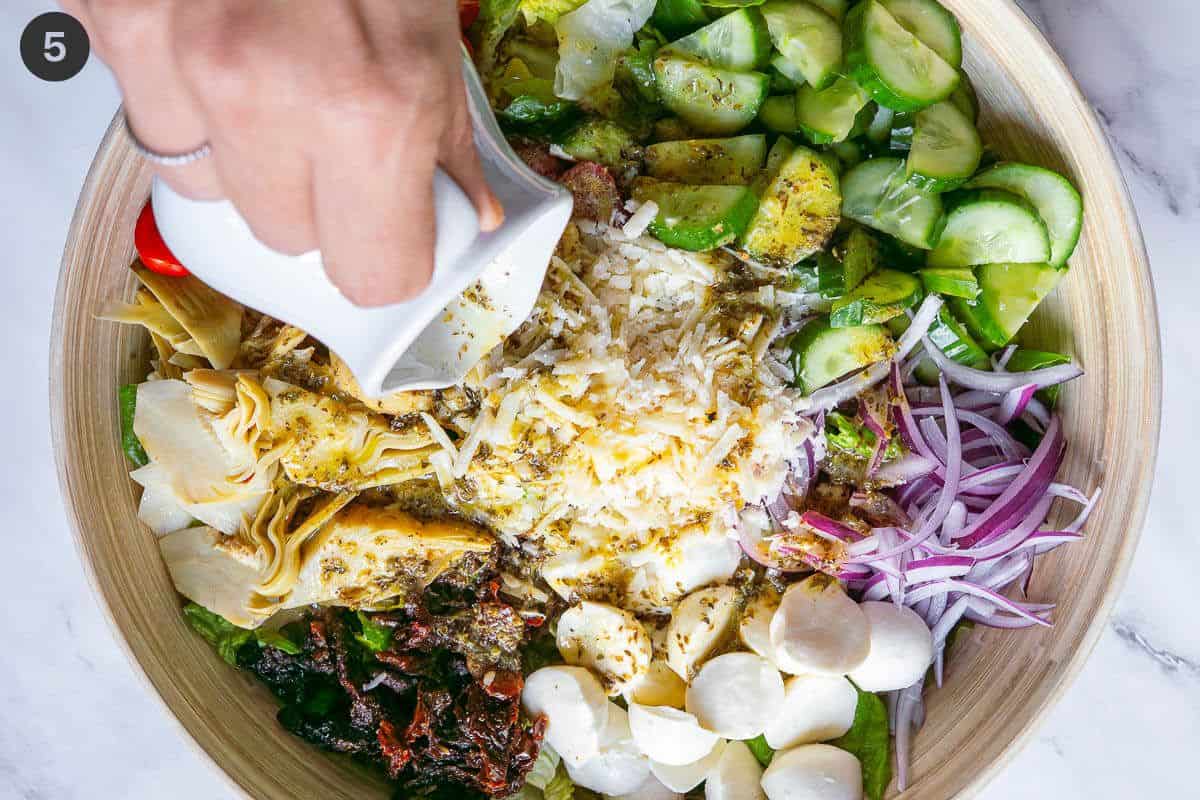 Dressing being poured over Italian Chopped Salad bowl