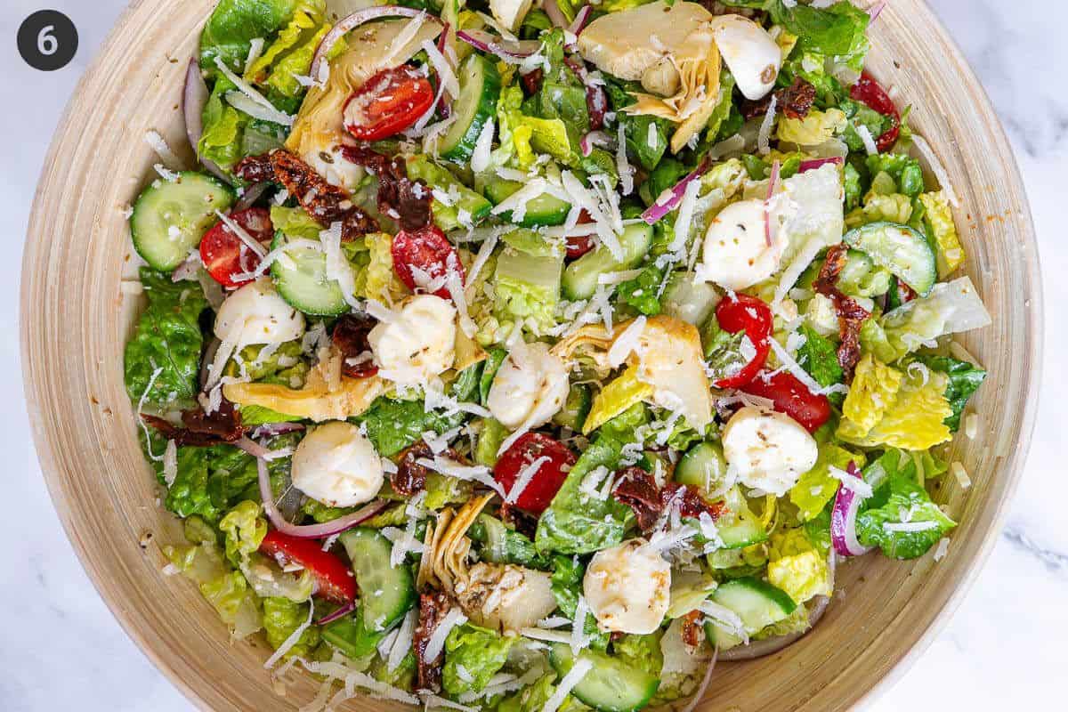 Salad mixed with dressing and topped with grated parmesan